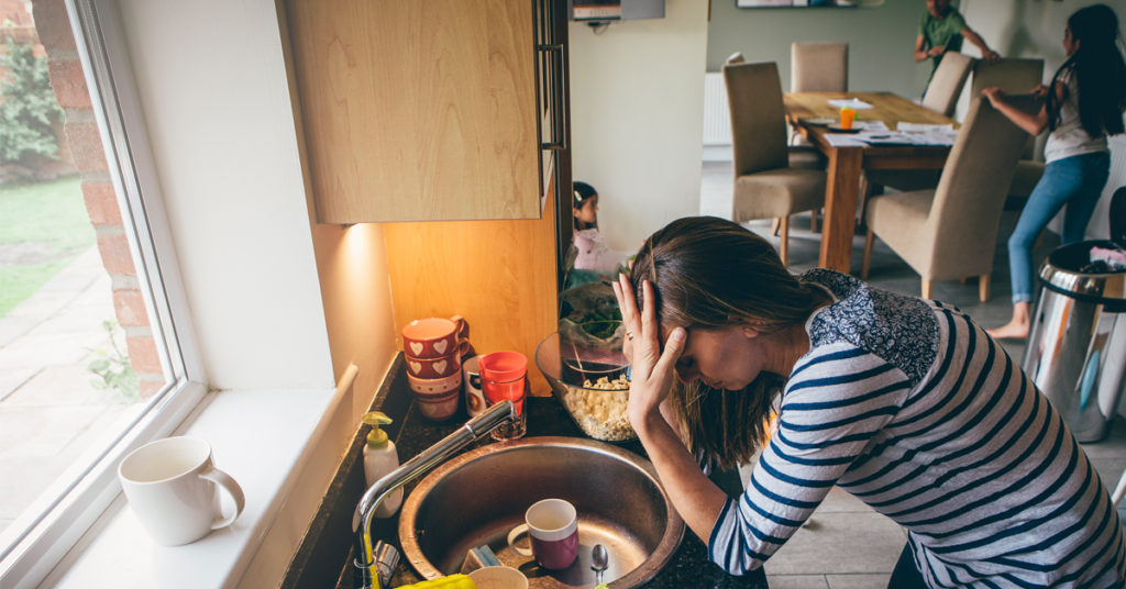 a woman holding her head standing over a sink