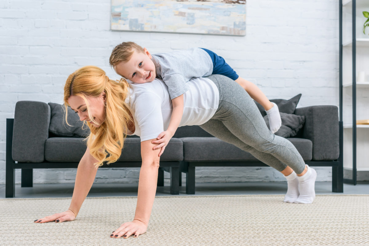 Mom doing yoga with her toddler son on her back