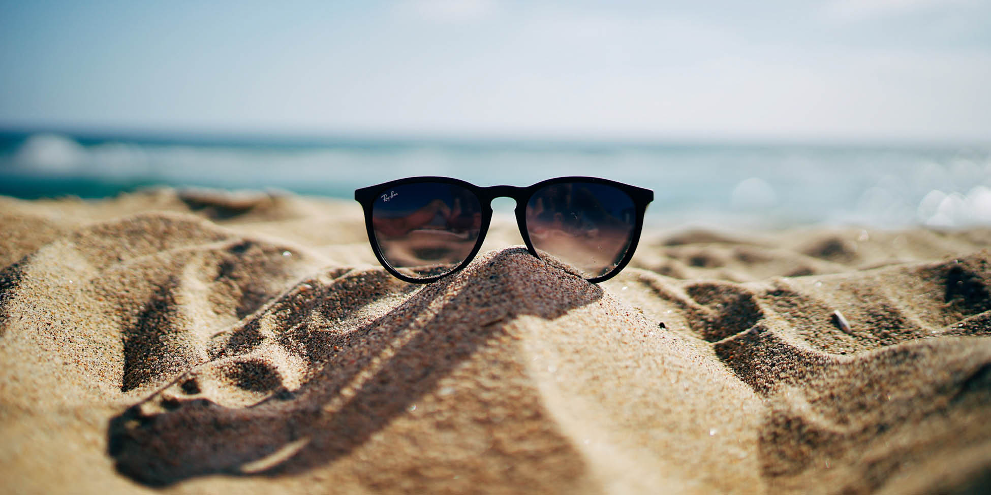 sunglasses resting on sand at beach