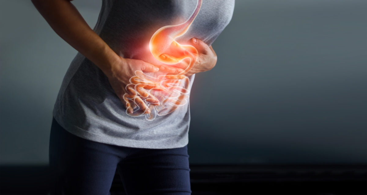 Woman touches painful stomach with digestive system showing