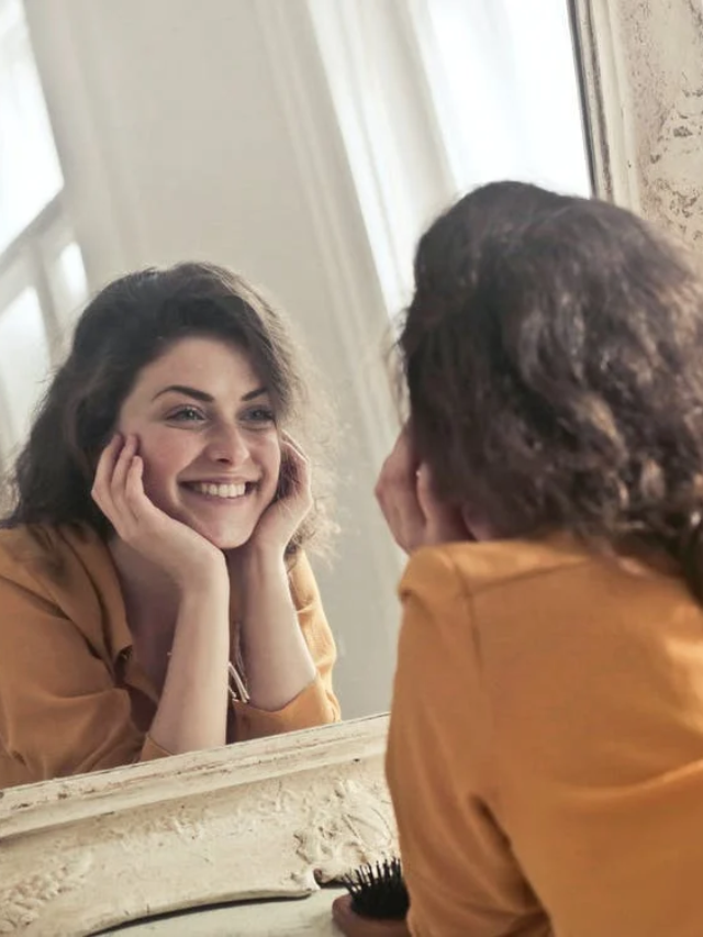IMAGE: young woman is looking into mirror and smiling