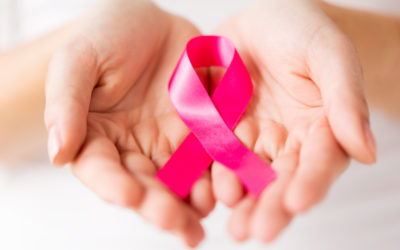 close up of woman cupped hands holding pink cancer awareness ribbon