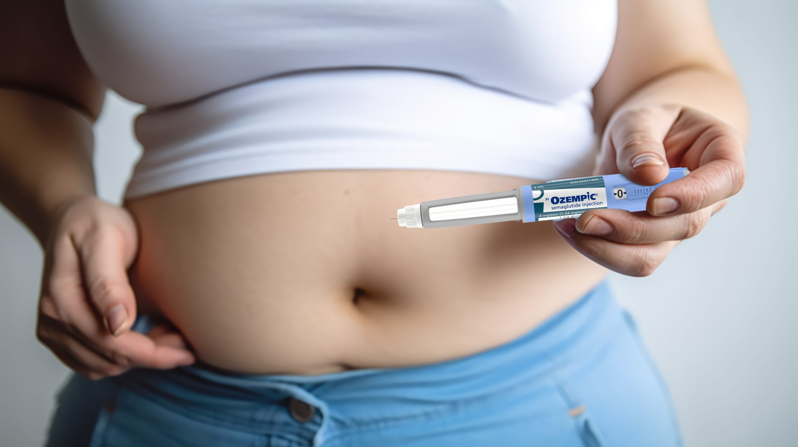 Woman holds ozempic injectable in front of stomach